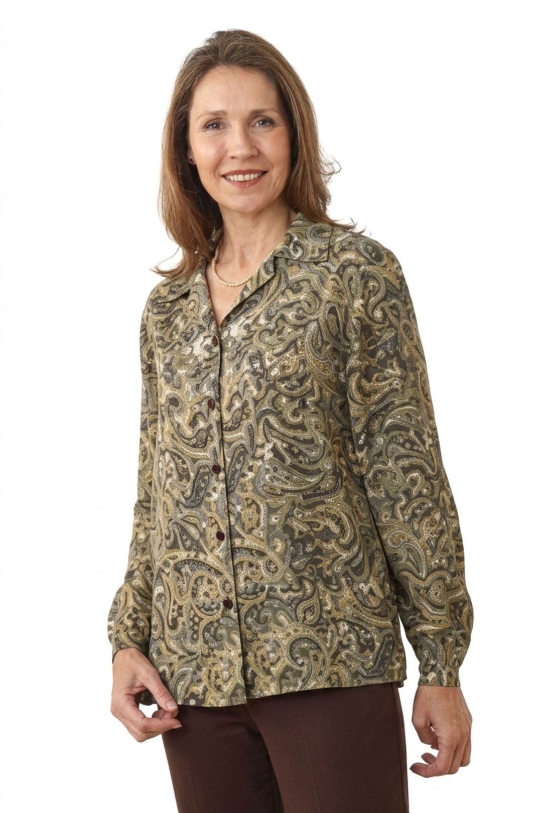A woman modeling a long-sleeve button-up blouse with an intricate paisley pattern in olive green, beige, and brown, paired with dark brown pants against a plain white background.