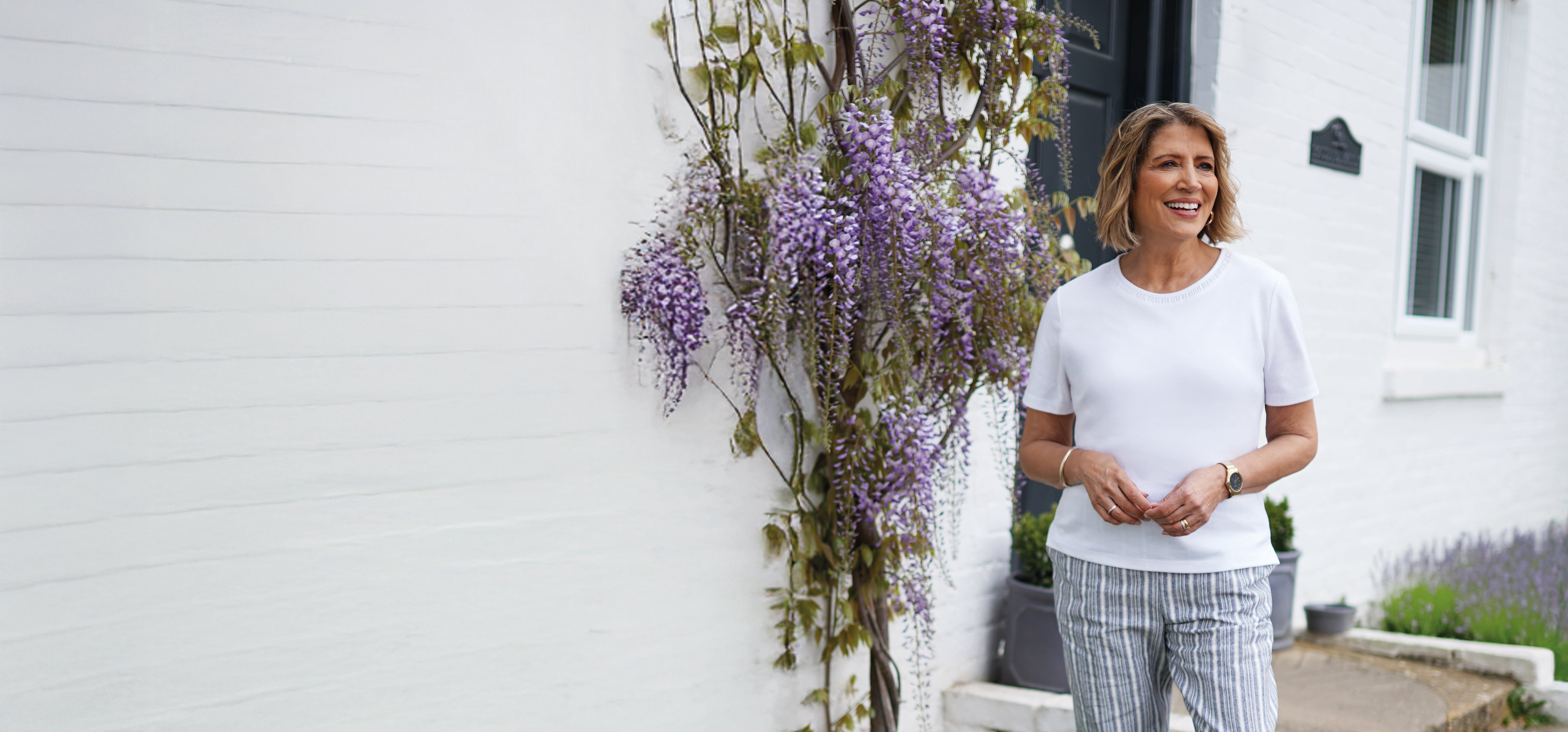 Woman standing outside a house with wisteria plants