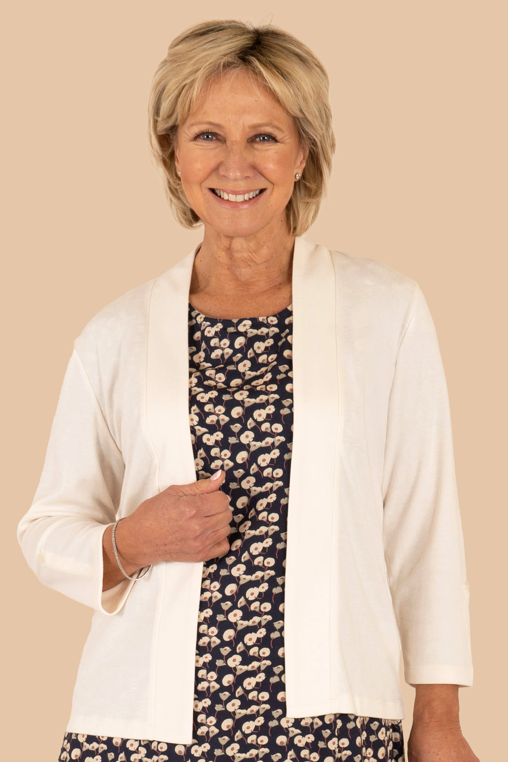 A woman wearing a white edge to edge jersey cardigan over a floral dress.