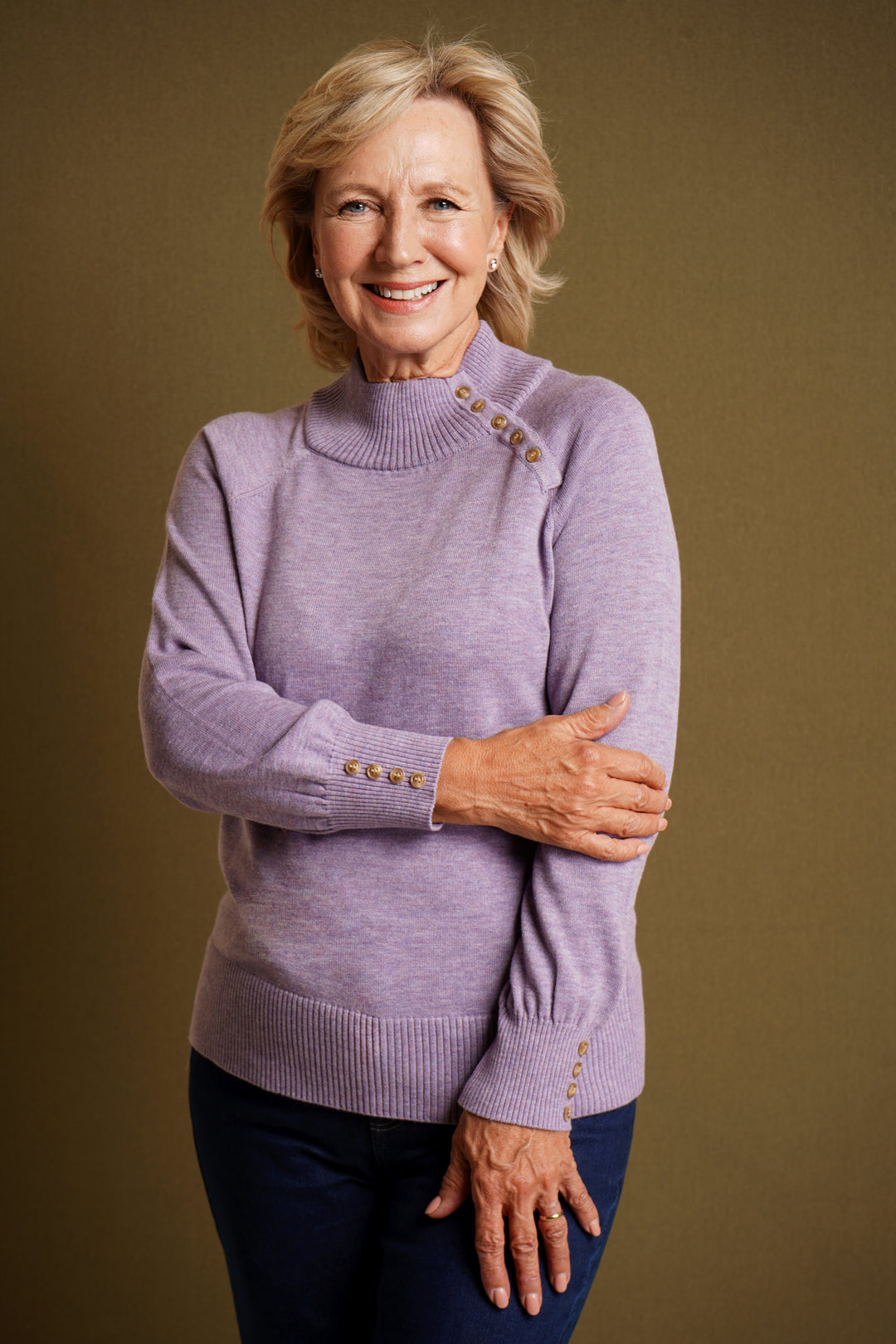 Woman wearing lilac sweater with decorative buttons on a brown background