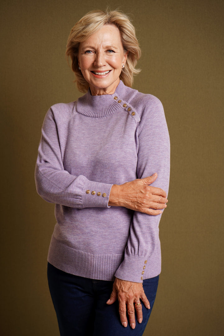 Woman wearing lilac sweater with decorative buttons on a brown background