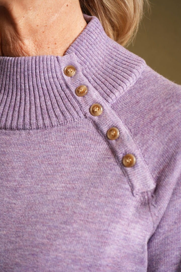 Close-up of a lilac sweater with gold buttons on a blurred background