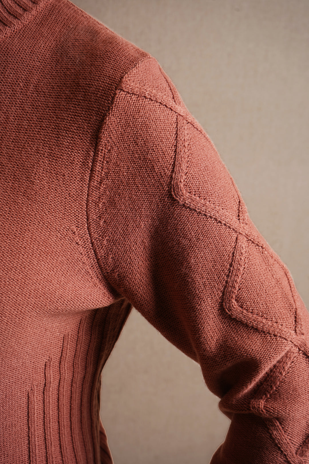 Close-up of a textured rosewood sweater sleeve against a neutral background