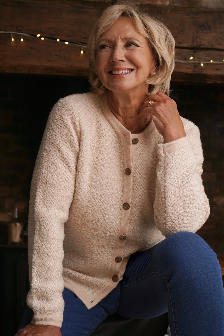 Woman wearing a beige cardigan with buttons in a cozy indoor setting.