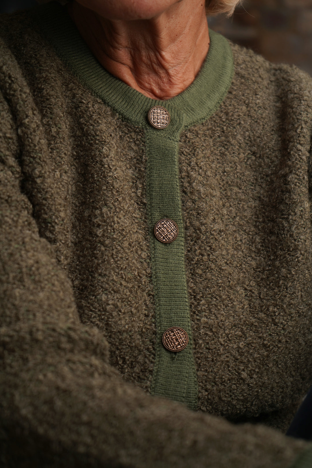 Close-up of a person wearing a green cardigan with buttons.