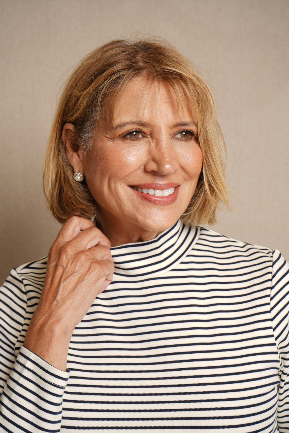 Woman wearing a navy and white striped shirt against a beige background.