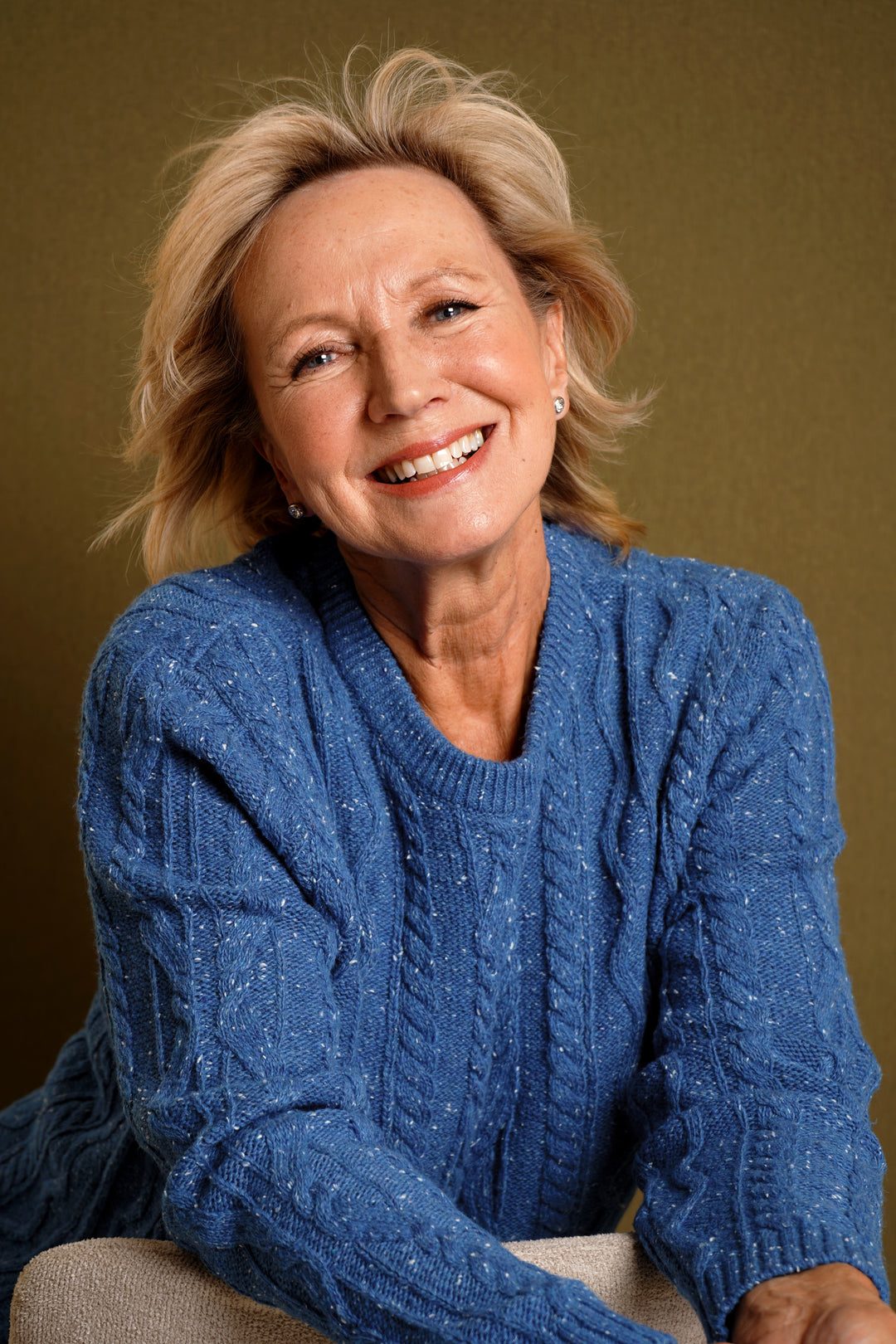 Woman wearing a blue sweater against a brown background