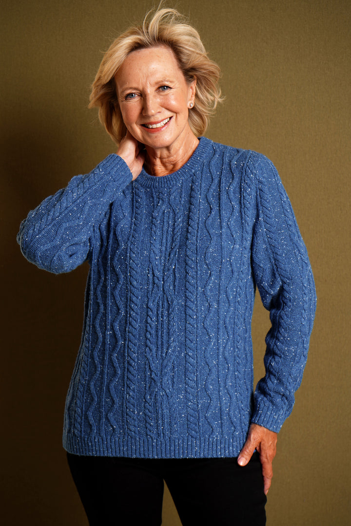 Woman wearing a blue cable knit sweater against a brown background