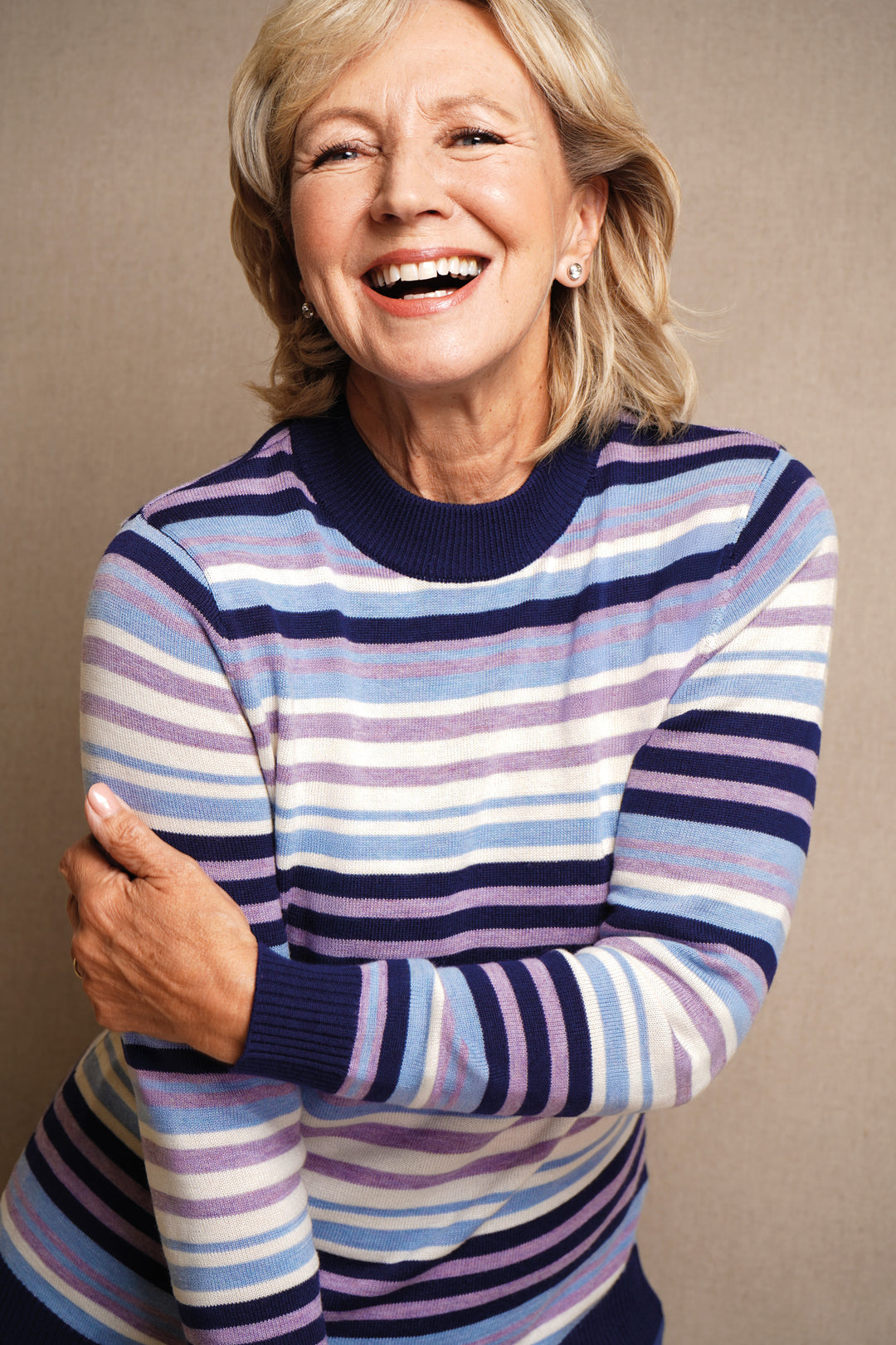 Woman wearing a striped sweater against a beige background