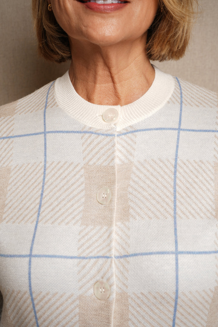 Close-up of a person wearing a white cardigan with blue checkered pattern