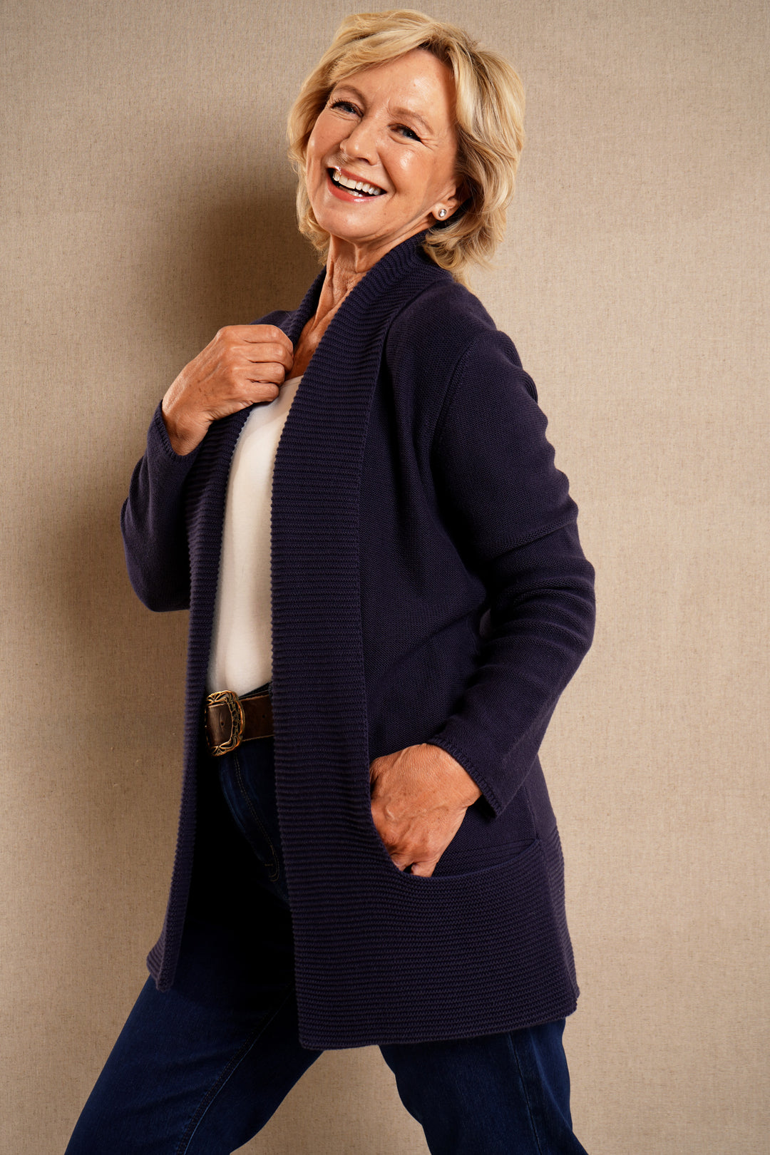 Woman wearing a navy cardigan over a white shirt with a beige background