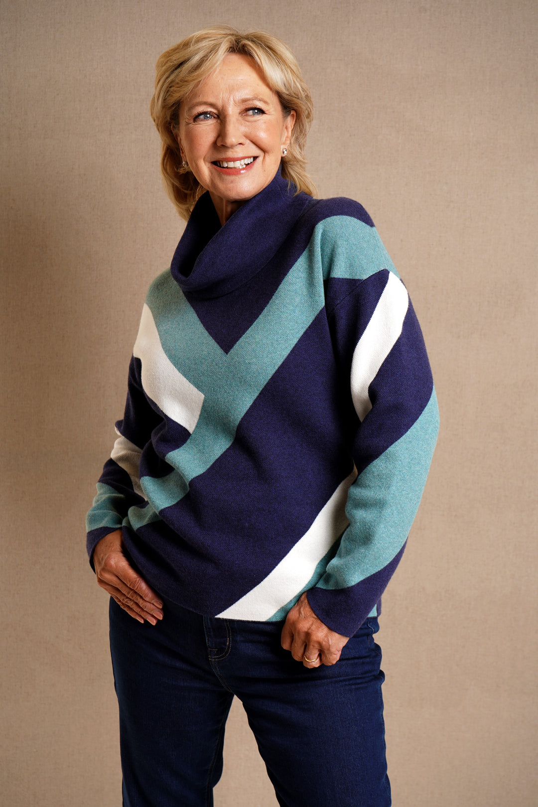 Woman wearing a colorful sweater with a chevron pattern against a beige background