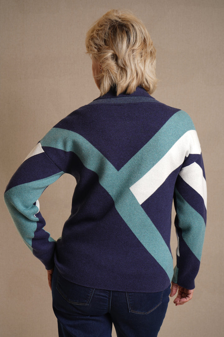 Person wearing a patterned sweater with blue, green, and white colors on a beige background