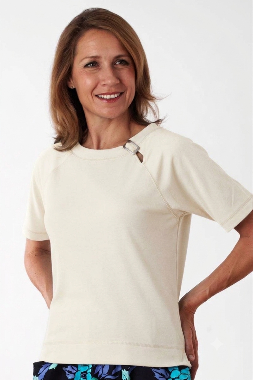 Woman wearing a white t-shirt with a decorative button on a plain background