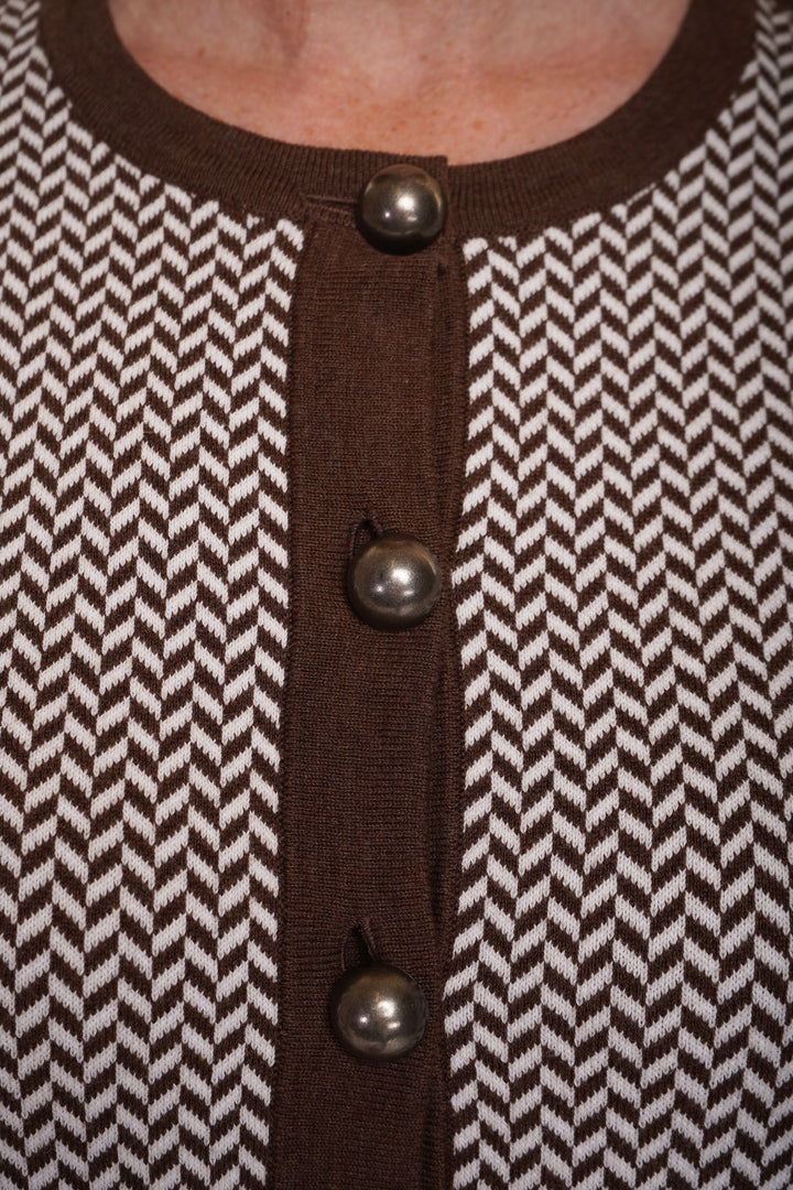 A close up of  brown cardigan with a herringbone pattern, featuring large buttons and dark brown trim.